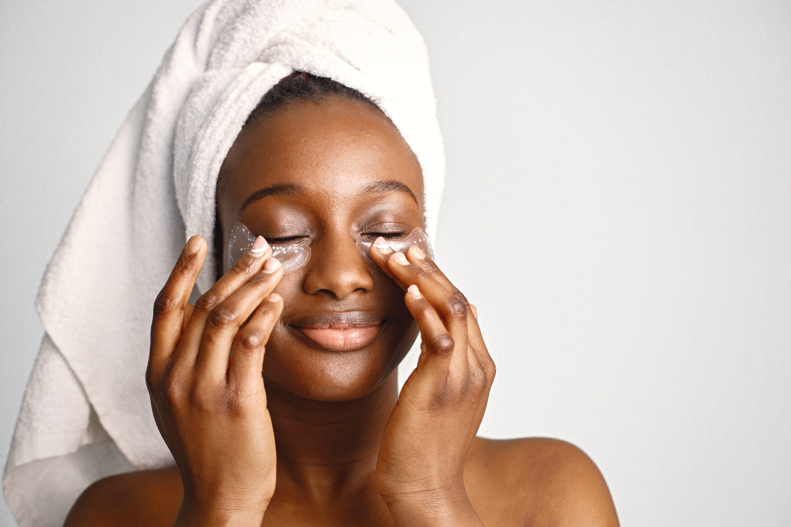 Black girl with towel on a head has eye patches isolated on whit